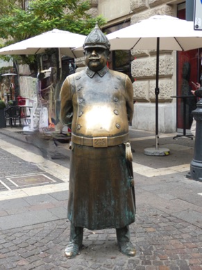 le "gros policier" jovial et corpulent, mains pos&eacute;es sur son ventre rond, v&ecirc;tu de l'uniforme traditionnel hongrois.