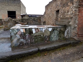 thermopolium avec un comptoir renfermant de grandes jarres, qui correspond a un snack bar